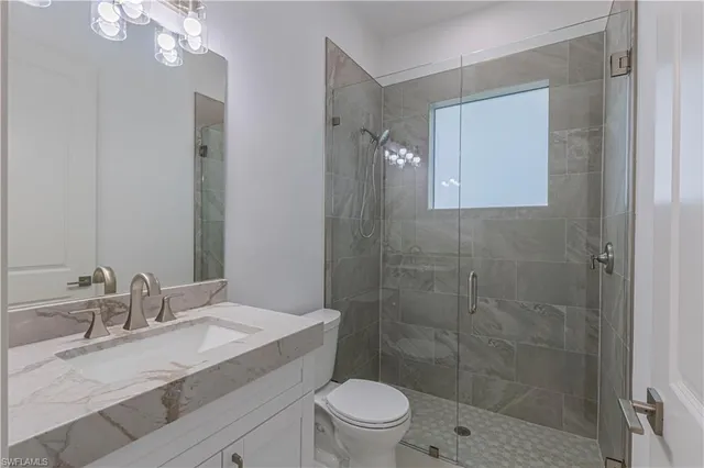 a bathroom with a granite countertop sink toilet a mirror and shower