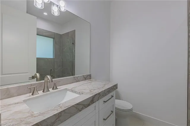 a bathroom with a granite countertop sink a toilet and a mirror