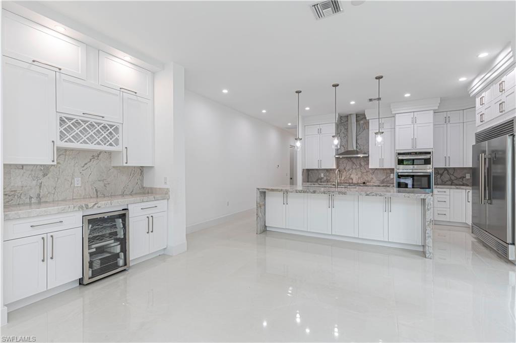 3074 Pine Tree Drive Naples, FL 34112 - Photo 6 of 18 a large kitchen with stainless steel appliances cabinets a sink and a stove
