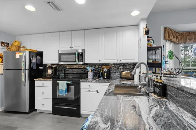 a kitchen with stainless steel appliances granite countertop a refrigerator stove and sink
