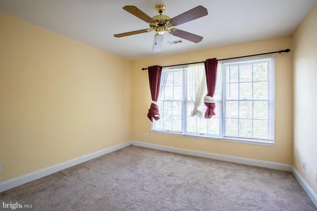an empty room with a window and a ceiling fan