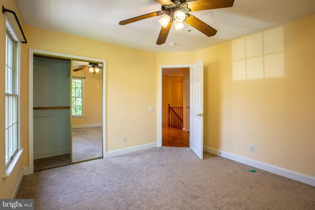 an empty room with closet and a chandelier fan