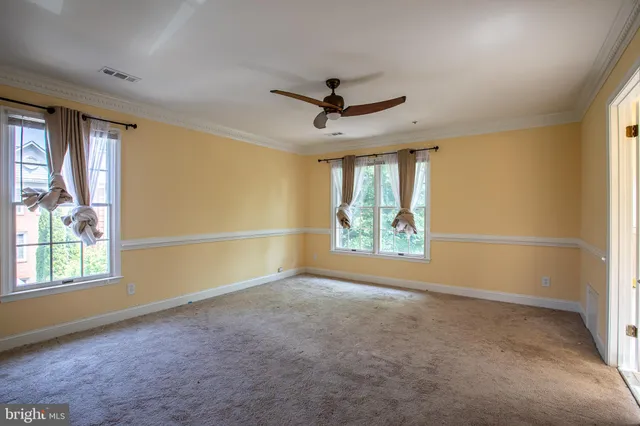 an empty room with windows and ceiling fan