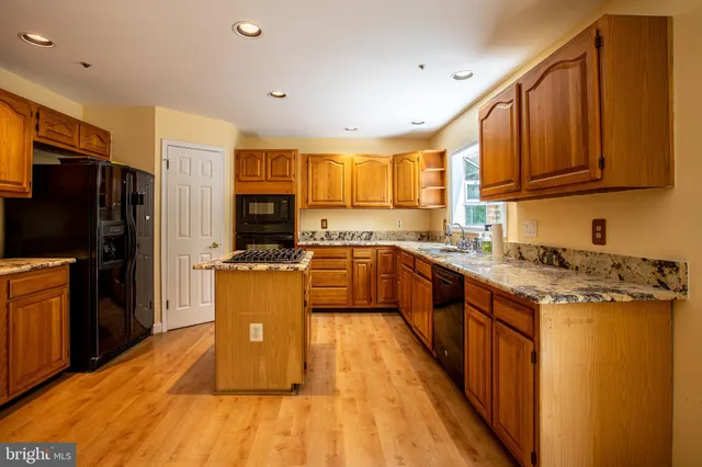 a kitchen with stainless steel appliances granite countertop a stove top oven a sink dishwasher a refrigerator and cabinets with wooden floor