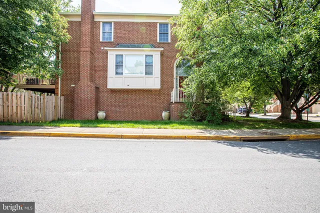a view of a brick house with a yard and large trees