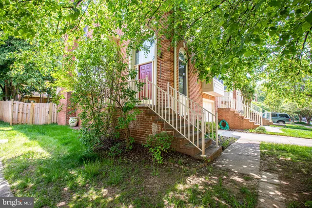 a view of a house with a small yard and large trees