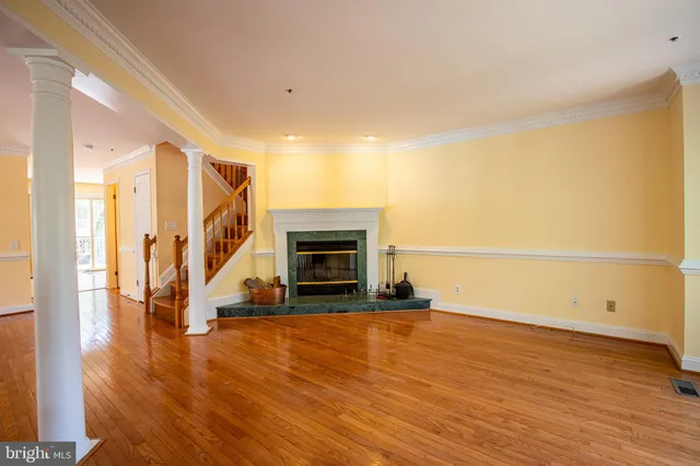 a view of an empty room with wooden floor and a fireplace