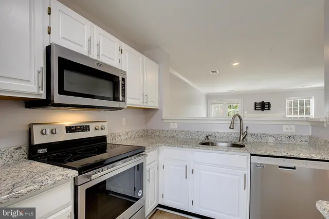 a kitchen with stainless steel appliances granite countertop white cabinets granite counter tops and a stove
