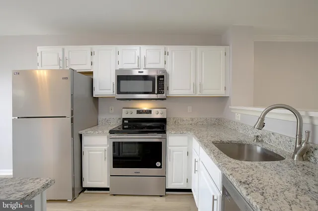 a kitchen with refrigerator a microwave a sink and cabinets
