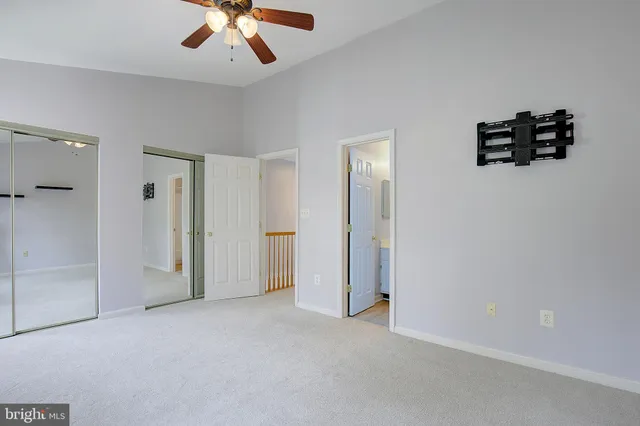 an empty room with windows and ceiling fan