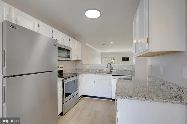 a kitchen with granite countertop cabinets stainless steel appliances and a counter space