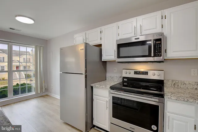 a kitchen with cabinets stainless steel appliances and a window