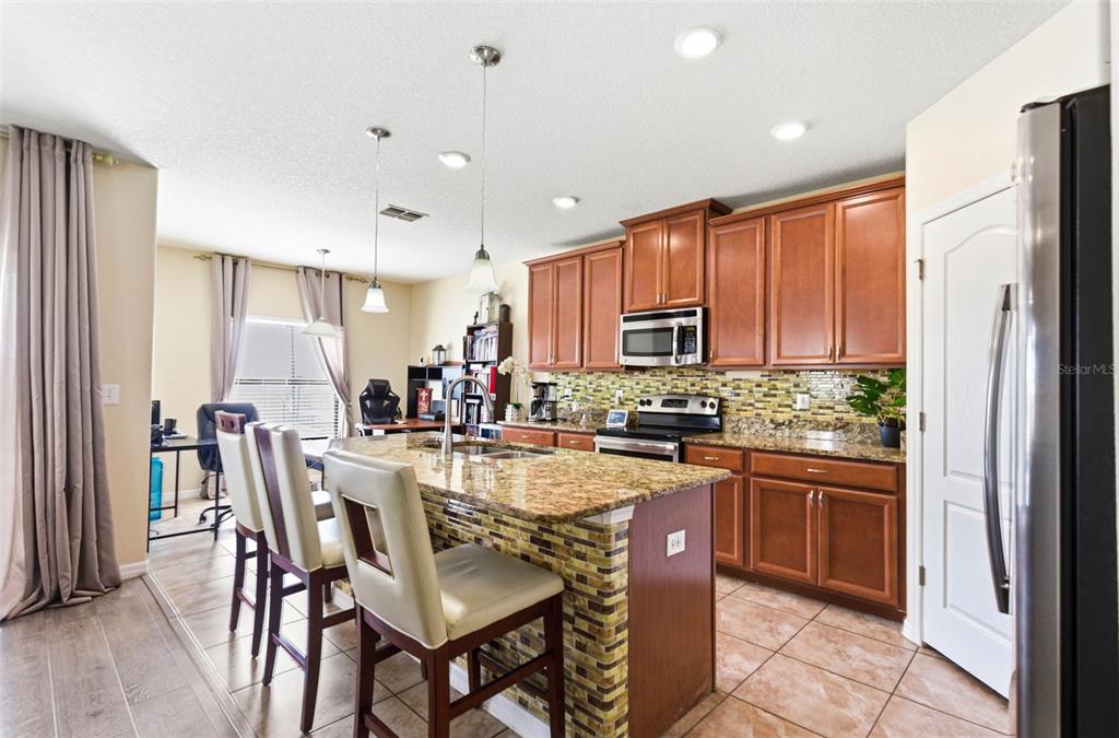 10135 Newminster Loop Ruskin, FL 33573 - Photo 11 of 35 a kitchen with stainless steel appliances granite countertop sink refrigerator dining table and chairs