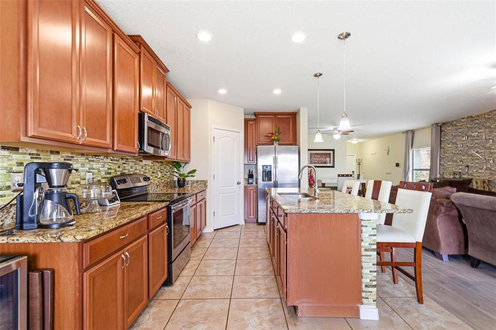 10135 Newminster Loop Ruskin, FL 33573 - Photo 13 of 35 a kitchen with stainless steel appliances granite countertop sink wooden cabinets and dining table