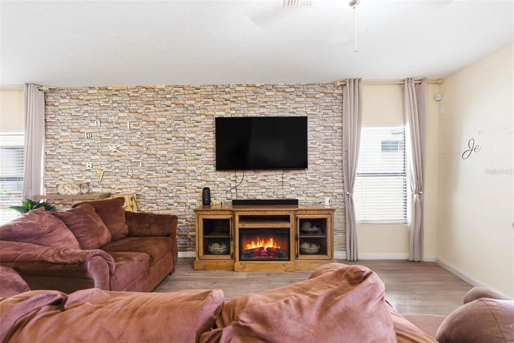 10135 Newminster Loop Ruskin, FL 33573 - Photo 7 of 35 a living room with furniture a fireplace and a flat screen tv