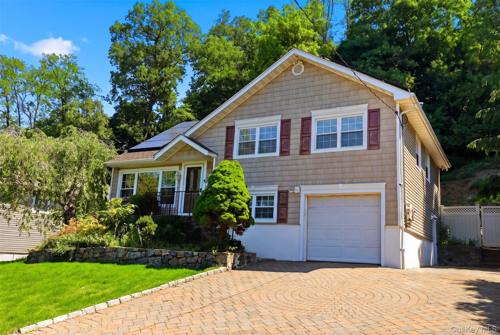 29 Montrose Road Yonkers, NY 10710 - Photo 2 of 39 Shingle-sided residence featuring a paver driveway, an attached garage, solar panels, and red decorative shutters