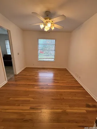 a view of an empty room with wooden floor and a chandelier