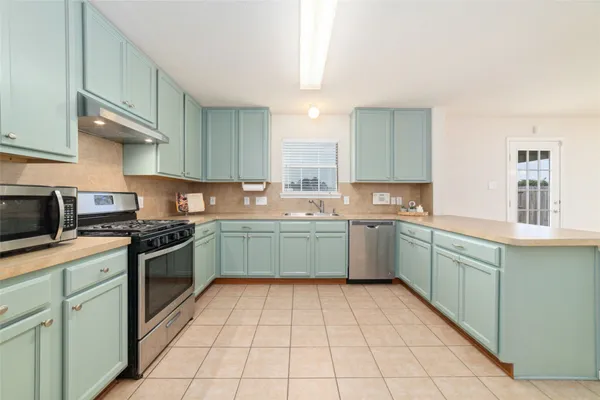 a kitchen with a sink a stove top oven and cabinets