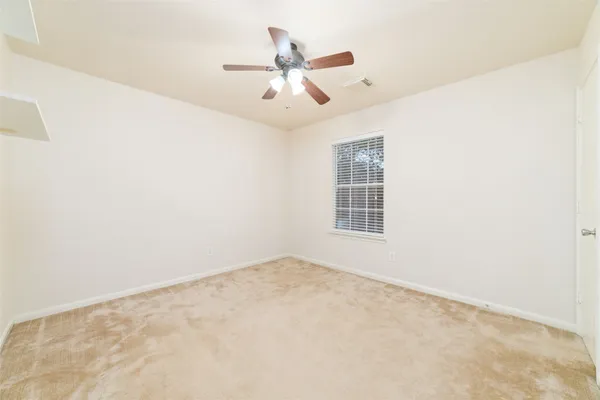 an empty room with ceiling fan and window