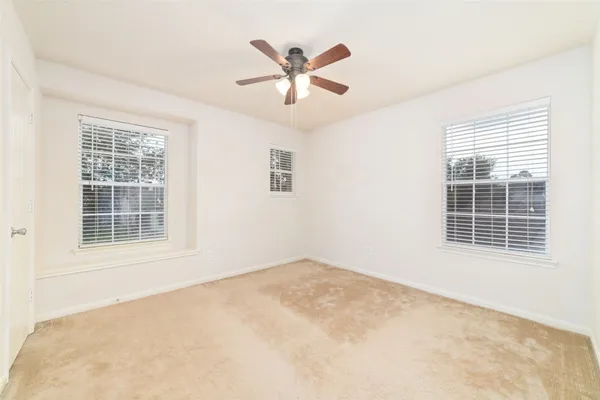 an empty room with ceiling fan and windows