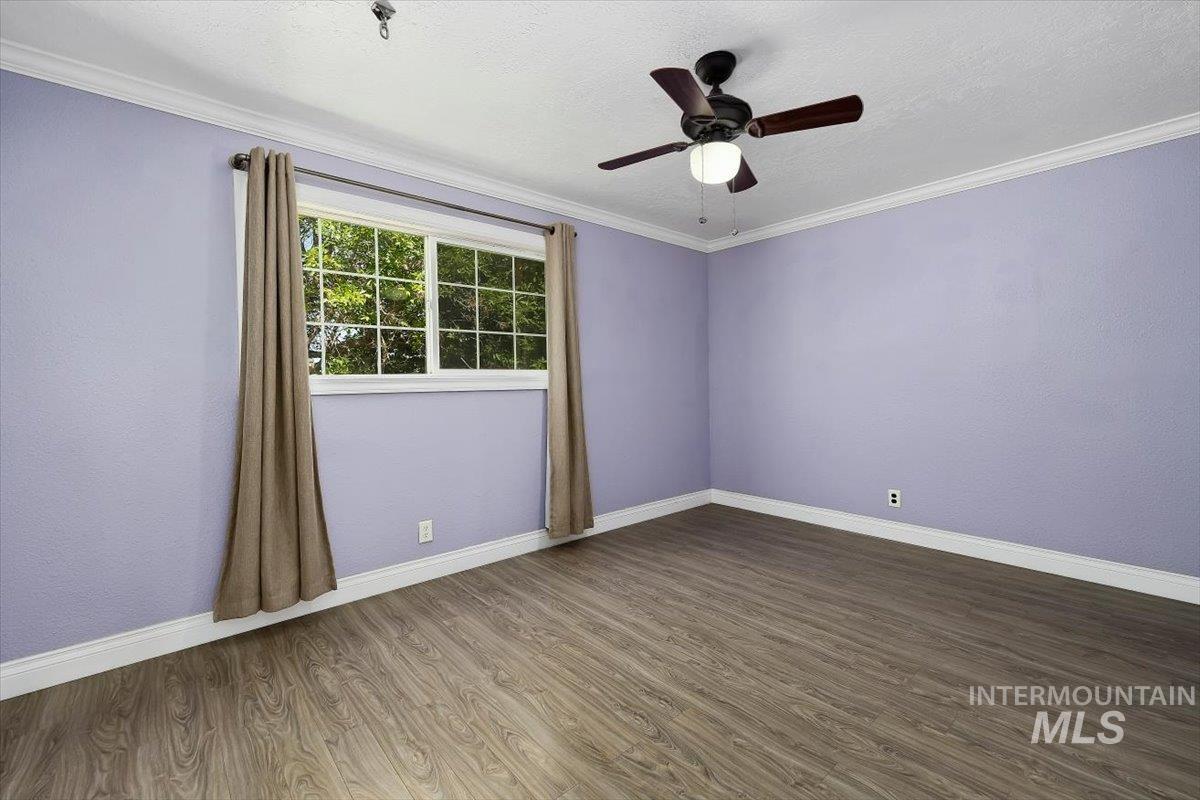 1940 Q Street Heyburn, ID 83336 - Photo 21 of 30 Spacious room featuring wood-finish flooring, a multi-pane window, crown molding, and a ceiling fan with integrated lighting