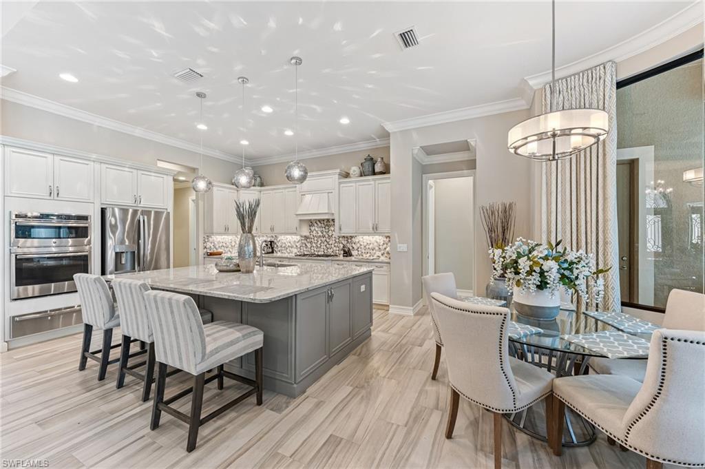 11974 Maidstone Court Naples, FL 34120 - Photo 13 of 45 Kitchen with white cabinetry, decorative backsplash, stainless steel appliances, a large island with sink, and recessed lighting