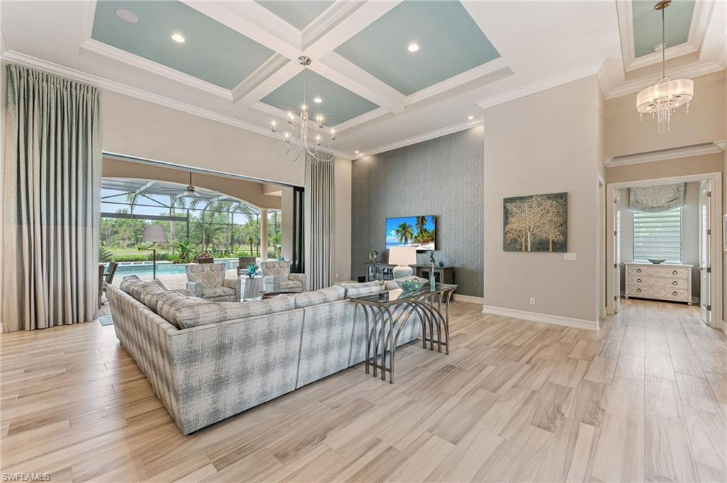 11974 Maidstone Court Naples, FL 34120 - Photo 17 of 45 Living area featuring a chandelier, healthy amount of natural light, a high ceiling, coffered ceiling, and ornamental molding
