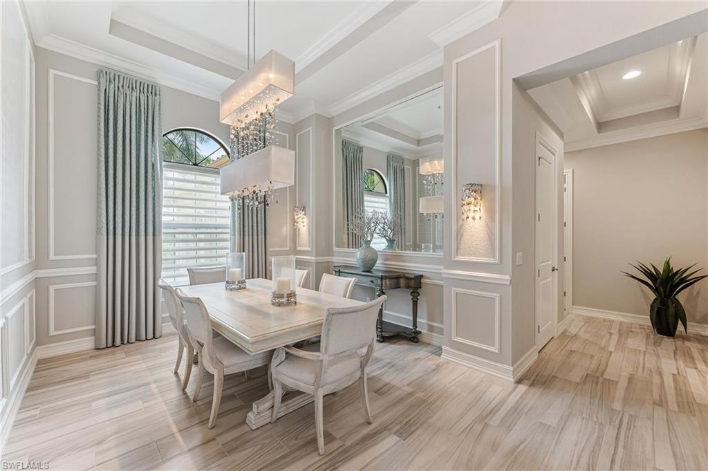 11974 Maidstone Court Naples, FL 34120 - Photo 20 of 45 Dining space featuring a decorative wall, a chandelier, ornamental molding, and a tray ceiling