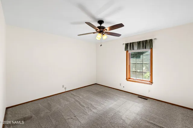 an empty room with a window and a fan