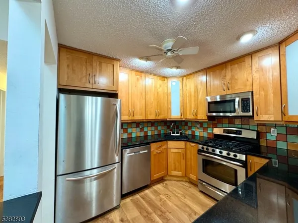 a kitchen with stainless steel appliances granite countertop a refrigerator a stove a sink and a microwave