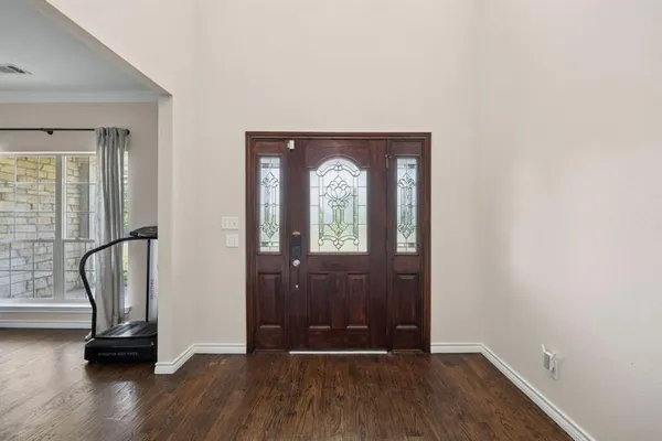 an empty room with wooden floor mirror and windows