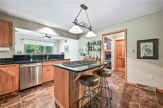 a kitchen with stainless steel appliances granite countertop a stove a sink dishwasher and a refrigerator with wooden floor