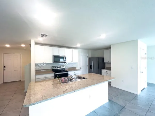 a kitchen with stainless steel appliances granite countertop a refrigerator stove a sink and a microwave