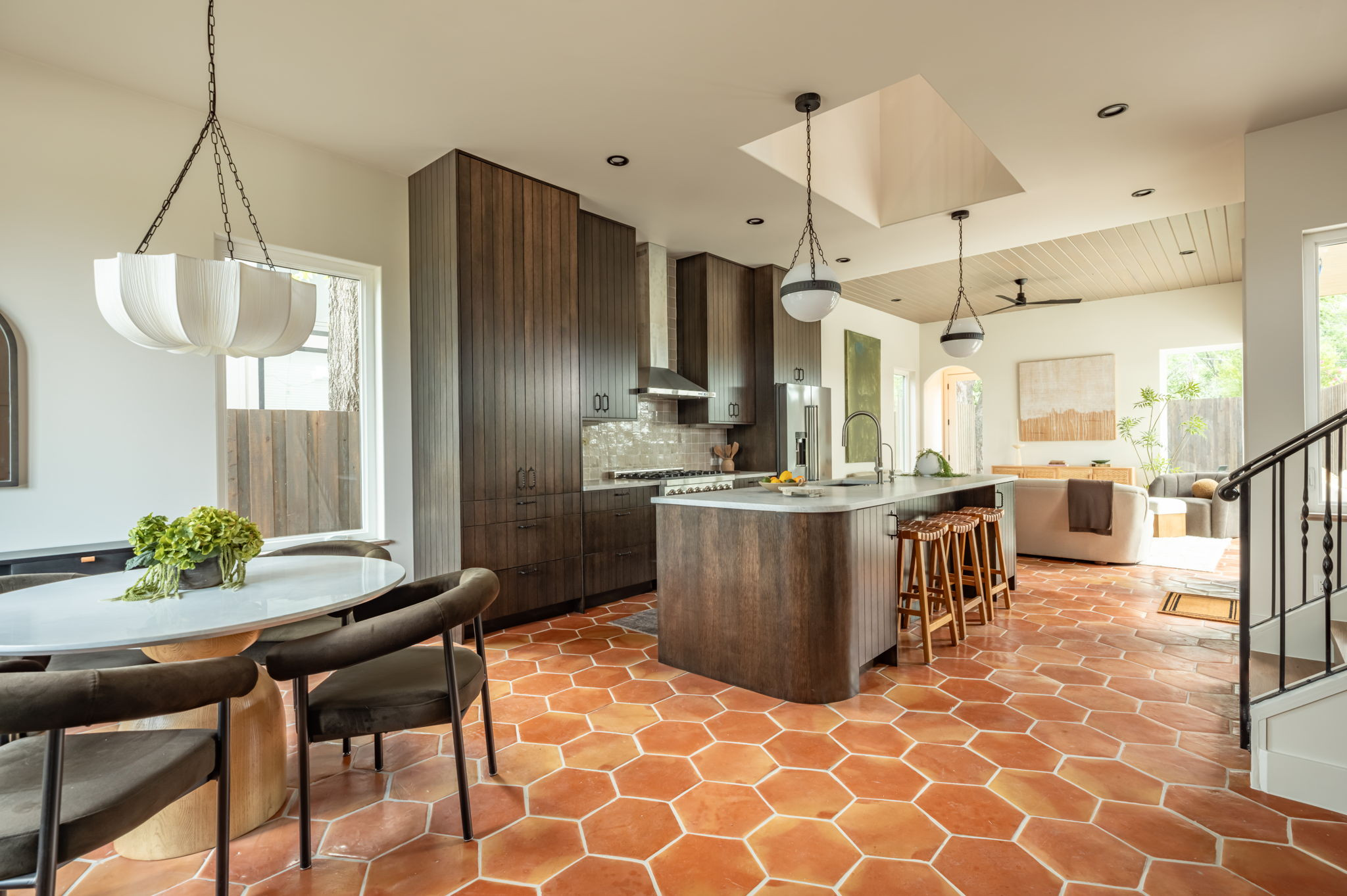 4713 Bolm Road Austin, TX 78702 - Photo 6 of 40 Open-concept kitchen featuring hexagonal terra cotta-style flooring, dark wood-finish cabinetry, a central island with countertop seating, and integrated stainless steel appliances