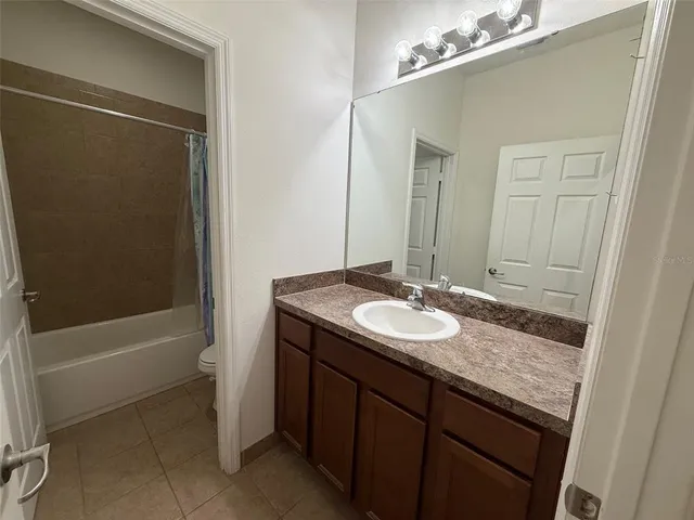 a bathroom with a granite countertop sink a toilet a mirror and shower