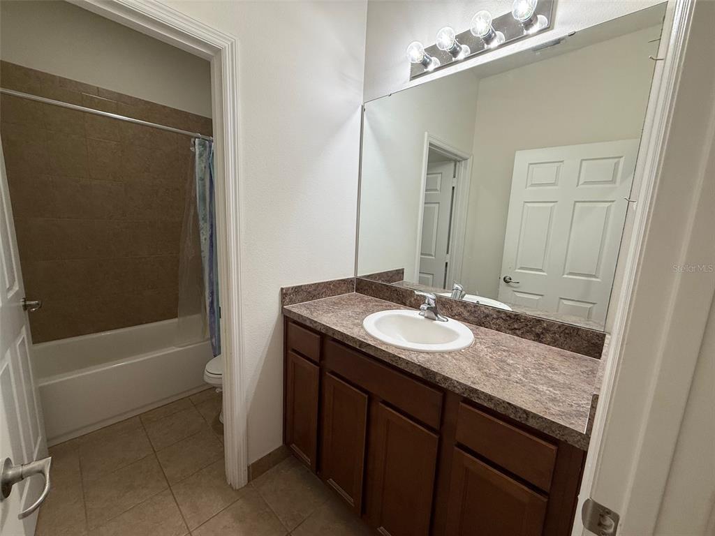 1766 Portofino Meadows Boulevard Orlando, FL 32824 - Photo 14 of 20 a bathroom with a granite countertop sink a toilet a mirror and shower