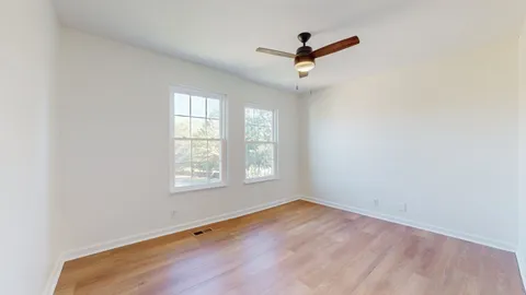 an empty room with a window and a ceiling fan