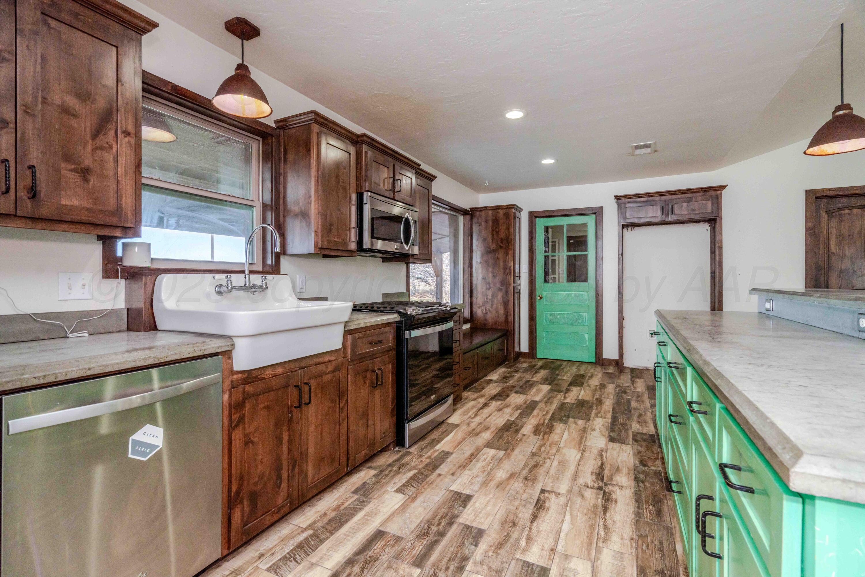 5490 West Rd R Dumas, TX 79029 - Photo 5 of 36 a kitchen with kitchen island granite countertop a sink stove and cabinets