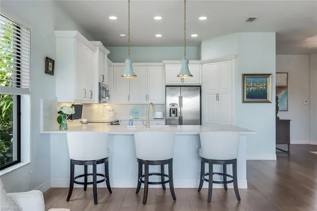 a kitchen with stainless steel appliances kitchen island granite countertop a dining table chairs and white cabinets