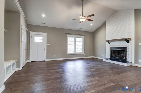 an empty room with wooden floor and a kitchen