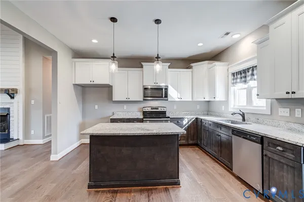 a kitchen with kitchen island a chandelier and wooden floor