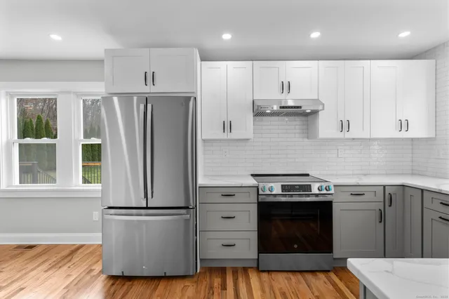 a kitchen with sink a refrigerator and white cabinets