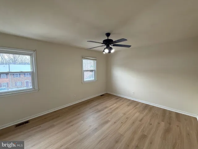a view of empty room with wooden floor and fan