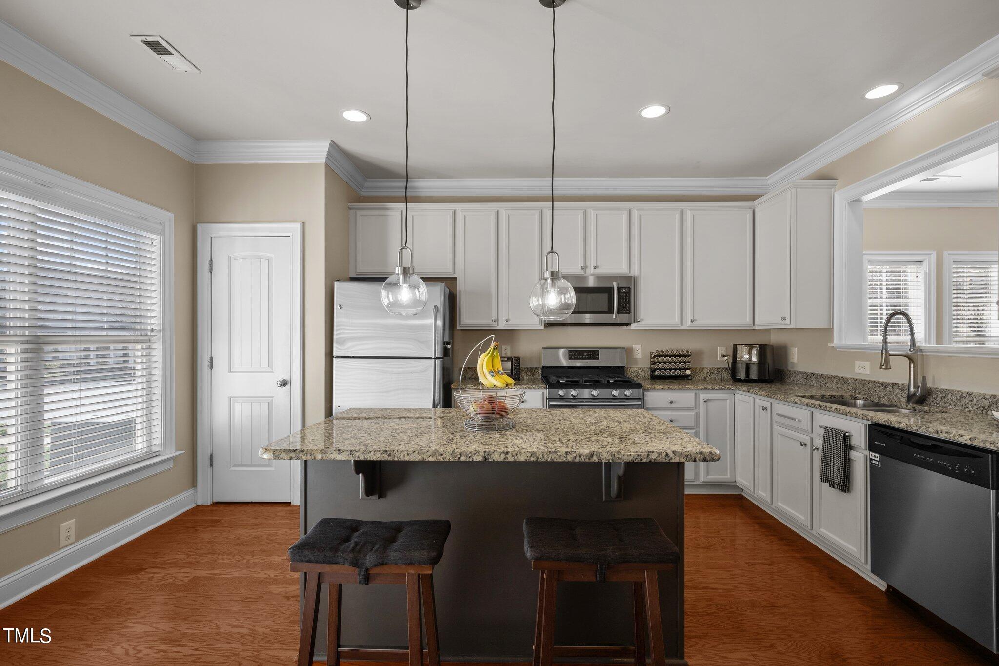 7765 Courtney Estates Drive Raleigh, NC 27617 - Photo 12 of 37 a kitchen with stainless steel appliances granite countertop a stove top oven a refrigerator a sink and dishwasher with wooden floor