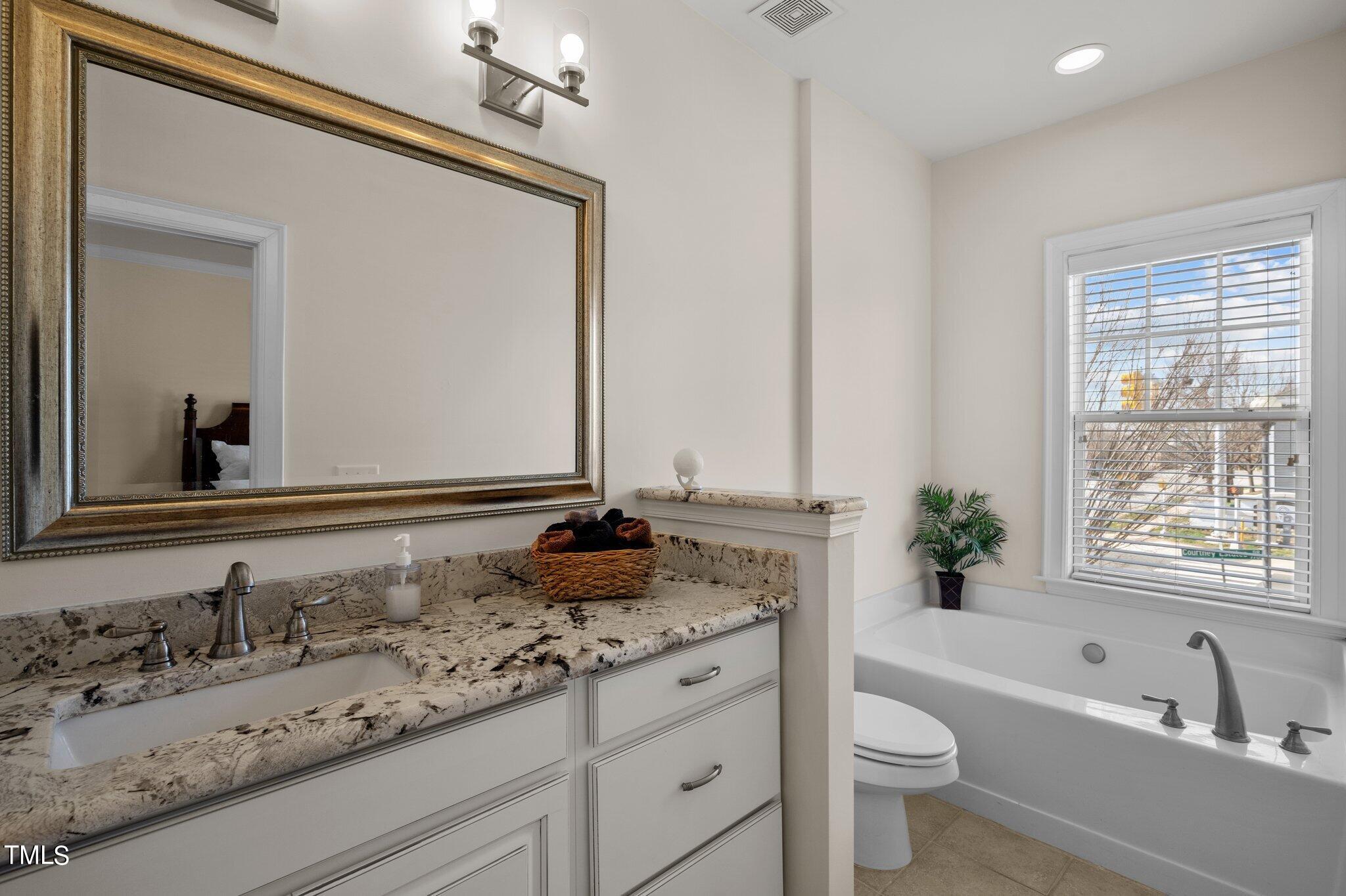 7765 Courtney Estates Drive Raleigh, NC 27617 - Photo 20 of 37 a bathroom with a granite countertop sink and a large mirror