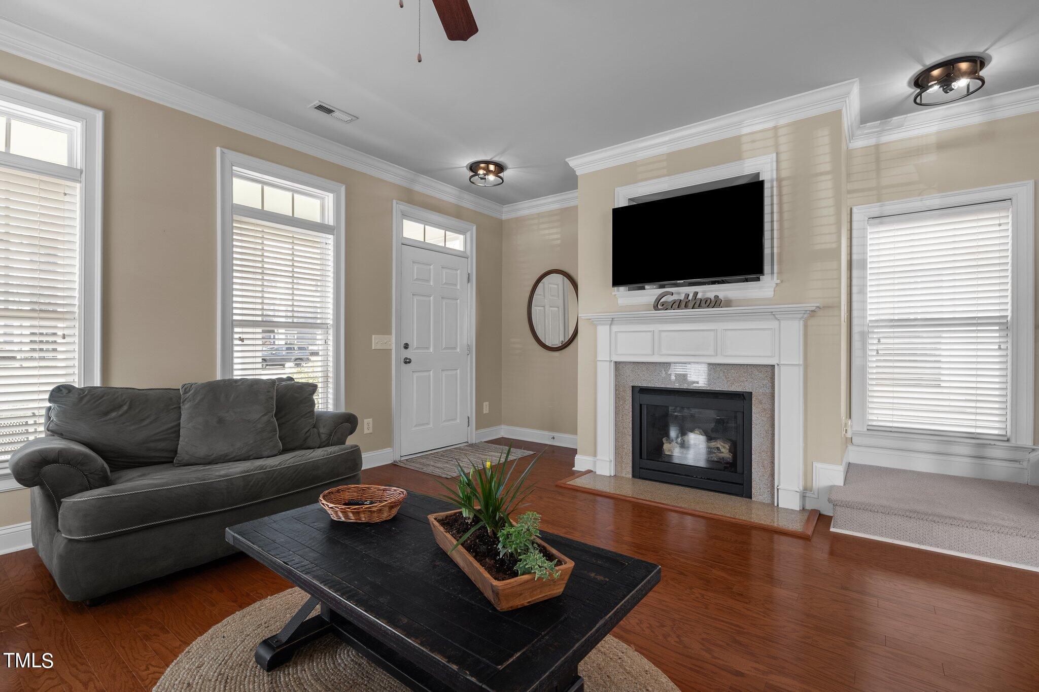 7765 Courtney Estates Drive Raleigh, NC 27617 - Photo 7 of 37 a living room with furniture a flat screen tv and a fireplace