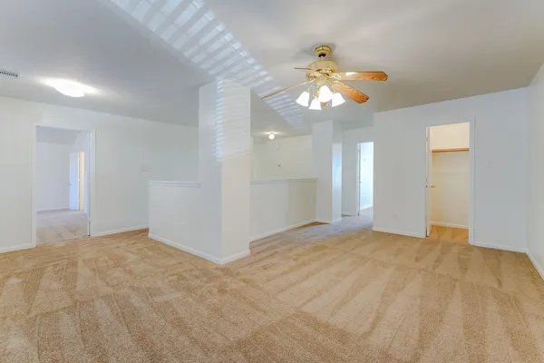 a view of an empty room with a chandelier fan