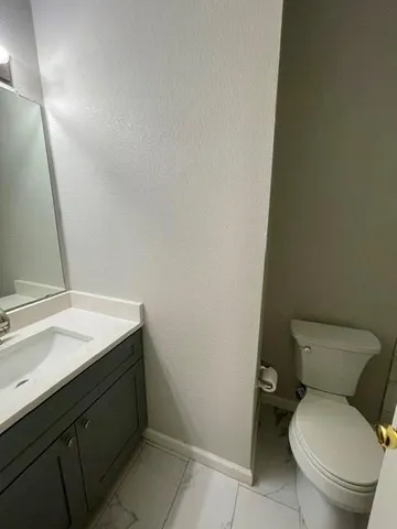 a bathroom with a granite countertop toilet and a sink