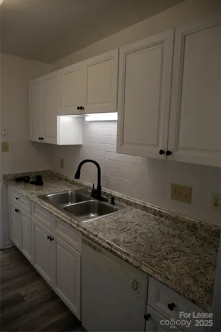 a kitchen with granite countertop white cabinets and sink