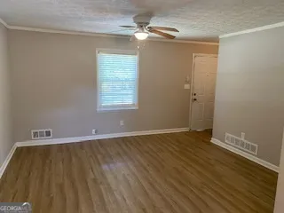 a view of an empty room with window and chandelier fan